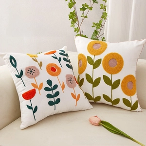 Detail of premium cotton pillowcase with textured 3D sunflower embroidery on beige sofa
