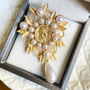 Detail of vintage gold matte brooch with Elizabeth II coin, pearls and leaf motifs