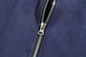 Macro shot of silver metal zipper and dual stitching on a slim navy blue jacket