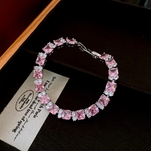 Macro shot of silver-toned bracelet with square pink zircons and small white diamonds