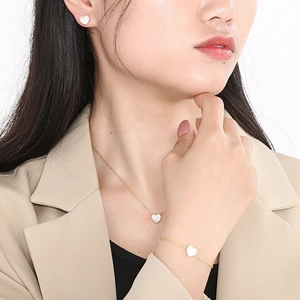 Elegant gold heart jewelry set with white mother of pearl on a female model