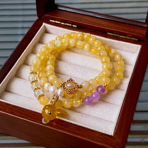 Macro shot of citrine beads and a gold hollow flower pendant with pearls in a wooden box