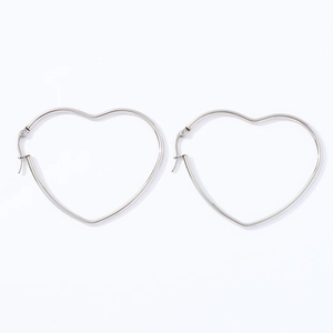 Detail view of a pair of silver heart-shaped stainless steel hoop earrings on white background