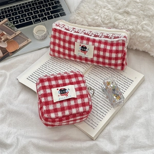 Detailed view of red plaid storage bags with lace trim in a cozy desk setting