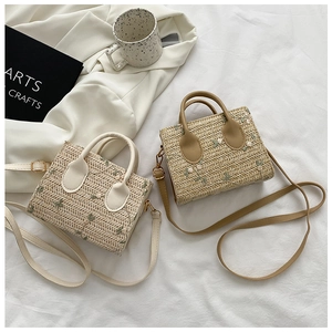 Detail of straw woven bags in beige and khaki featuring floral embroidery and straps