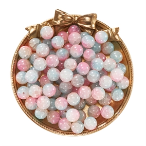 Detail view of 10mm pink and blue gradient glass beads on a gold tray for DIY jewelry