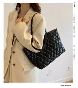 Detailed view of black quilted tote bag with large diamond patterns and soft padded texture