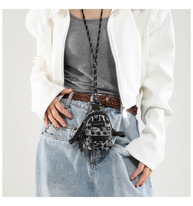Close-up of leopard print mini bag worn as a trendy necklace accessory over white jacket