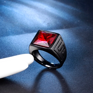 Macro shot of black stainless steel ring featuring a square red gemstone and geometric carving