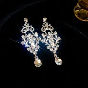Elegant silver teardrop chandelier earrings with pavé crystals on a black background