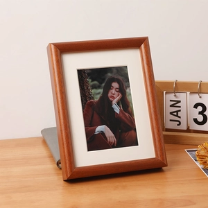 Elegant solid wood photo frame with cream mat board displayed on a wooden desk