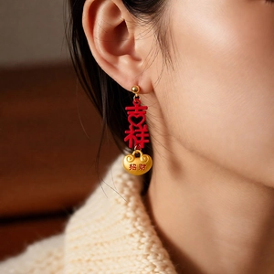 Macro view of Chinese New Year earrings featuring red enamel lucky charms and golden tassels