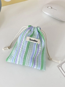 Striped seersucker drawstring storage pouch on desk for cosmetics and travel essentials
