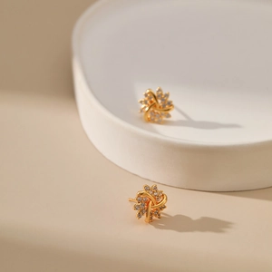 Detail of elegant gold swirl heart stud earrings with cubic zirconia on a pedestal