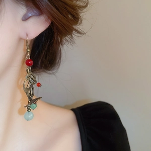 Détail des boucles d'oreilles rétro avec feuille de bronze et perles sur un modèle