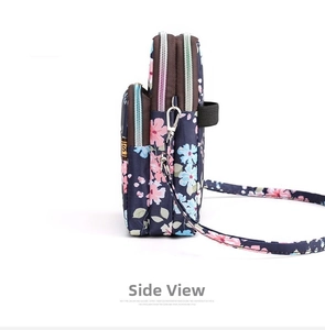 Detail view of the triple zipper compartments and floral nylon fabric on a crossbody bag