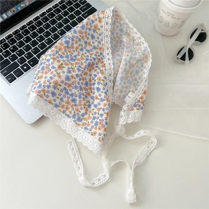 Flat lay of floral cotton triangle scarf with white lace trim and orange flower patterns