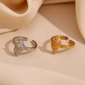 Detailed shot of gold and silver seashell open rings on beige fabric backdrop