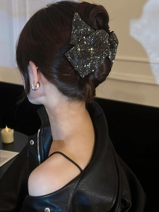 Close-up of a sparkling rhinestone bow hair claw clip worn on a bun hairstyle