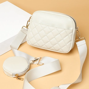 White quilted crossbody bag with wide strap and mini coin purse on geometric pedestal