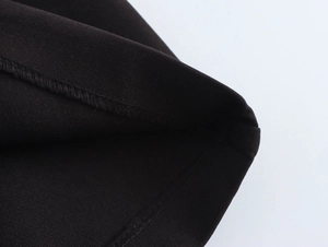 Detailed close-up of double stitching and woven fabric texture on black low-rise shorts