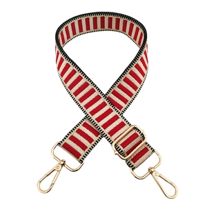 Detail of red and beige striped bag strap with premium gold metal clips and hardware