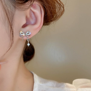 Gros plan sur des boucles d'oreilles nœud double en argent avec strass scintillants