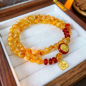 Detail of a double-layered beaded bracelet with yellow crystal beads and golden charms