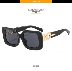 Close-up of black square sunglasses with grey lenses and gold chain link temple detail