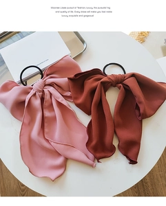 Detail of pink and brick red chiffon bow scrunchies with long ribbons on white table