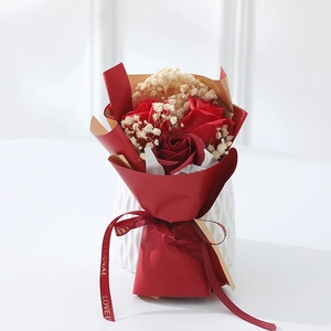 Detailed close-up of mini red rose and baby breath bouquet in red and gold wrapping paper