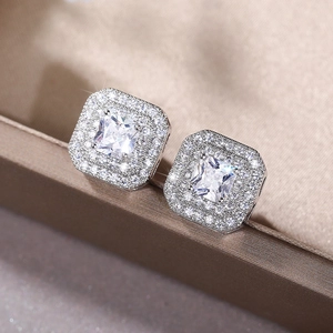 Macro shot of silver square halo earrings with cubic zirconia on luxury velvet background