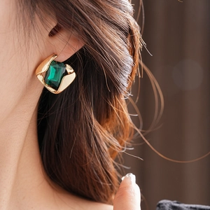 Detailaufnahme eines Vintage Gold-Ohrrings mit einem rechteckigen smaragdgrünen Stein