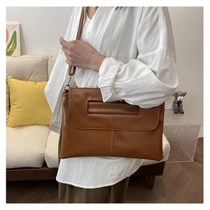 Detail of vintage brown PU leather crossbody bag with fine stitching and slim strap