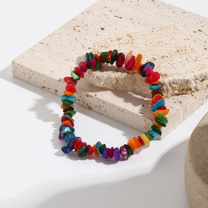 Detail of bohemian colorful natural crushed stone stretch bracelet on stone background