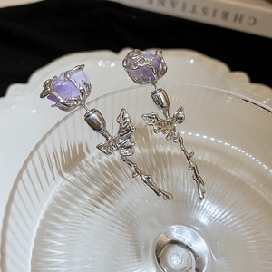 Detailed macro view of silver rose earrings with purple crystals and realistic thorn stems