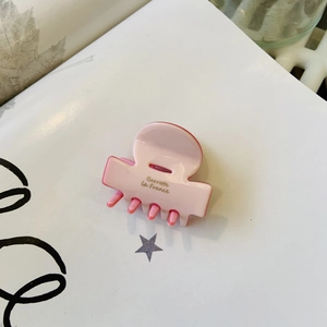 Detail of pink acetate hair claw clip featuring golden Barrette la France script