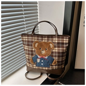 Detail of checkered tote bag featuring a cute brown plush bear patch by a sunny window