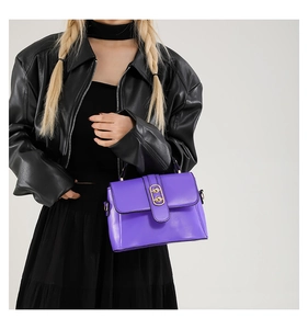 Detail of bright purple crossbody bag with golden metal lock on a black leather outfit