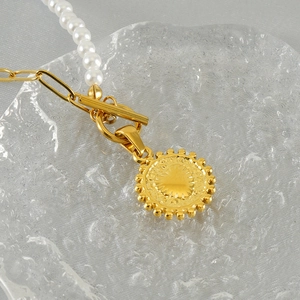 Golden titanium steel pearl necklace with OT buckle and heart pendant on clear tray