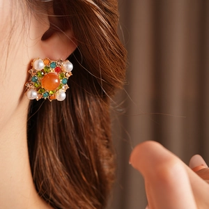 Gros plan sur des boucles d'oreilles carrées dorées avec perles et strass colorés