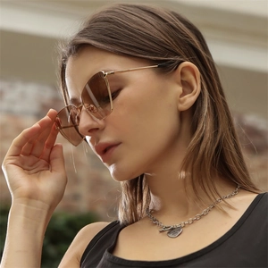 Detail of Y2K metal cat-eye sunglasses with brown gradient lenses on a fashion model