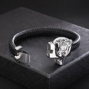 Detailed view of silver wolf head charm and clasp on black braided leather bracelet