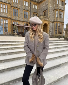 Detail of plaid blazer with faux fur cuffs and a grey chain handbag on stairs