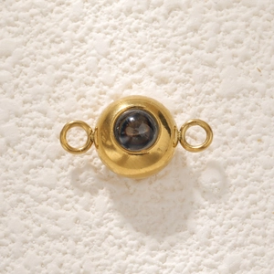 Macro shot of a golden stainless steel connector charm with circular dark projection stone