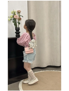 Rear view of girl wearing a pink quilted star chain bag with white polka dot hair tie