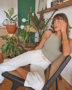 Dettaglio di un body all'americana verde da donna con pantaloni bianchi in un interno