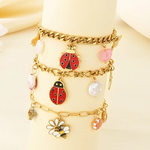 Detail of gold bracelets with bee, ladybug, heart and pearl charms on display stand