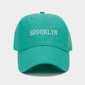 Close-up of white Brooklyn embroidery on mint green cotton baseball cap with fabric texture