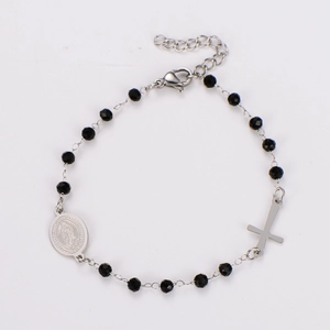 Close-up of black faceted prayer beads bracelet with silver oval cross and religious medal
